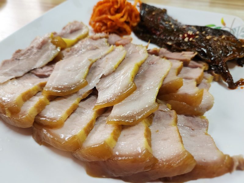 얇게 썬 수육과 무생채, 묵은지를 곁들인 접시