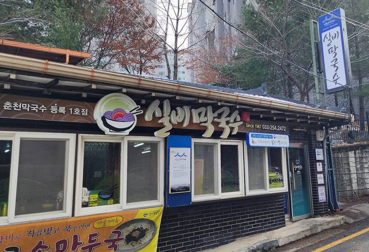 로고 간판을 단 실비막국수의 낮은 건물