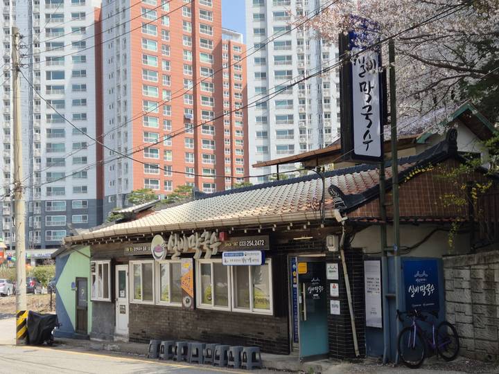 봄꽃 아래 세로 간판 ‘실비막국수’가 선 기와지붕 가게